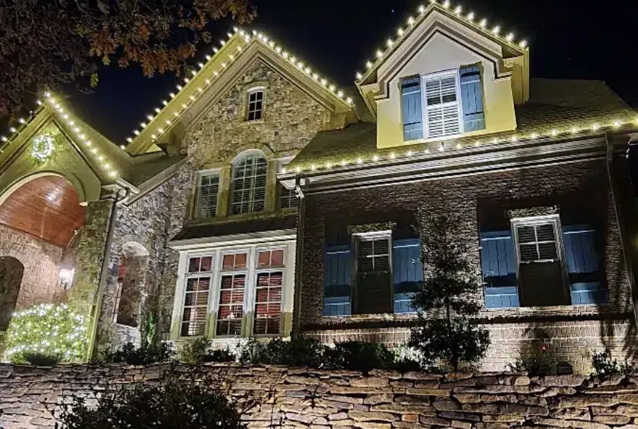 Shuttered stone-and-brick front with lit gables and soft light on the wall.