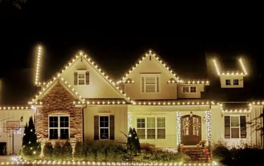 Stone and brick home with a warm white roofline glowing in the evening.